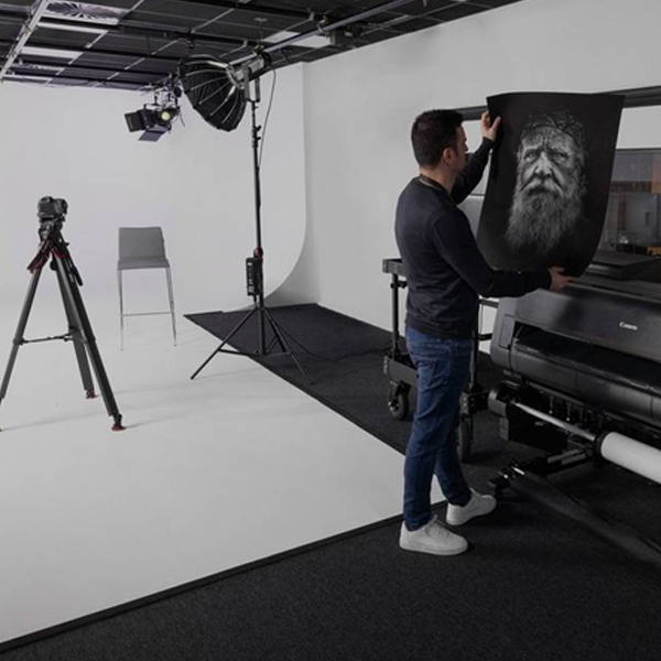 An empty photographic studio, with no people present. The studio is equipped with professional photography gear like tripods, lighting equipment, soft